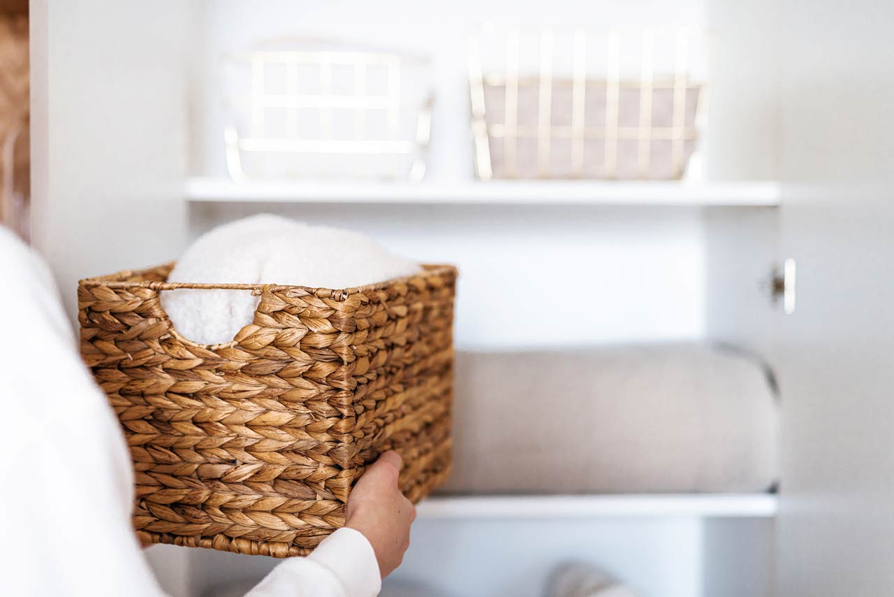 Woman organizing clothes on shelves in white opened wardrobe