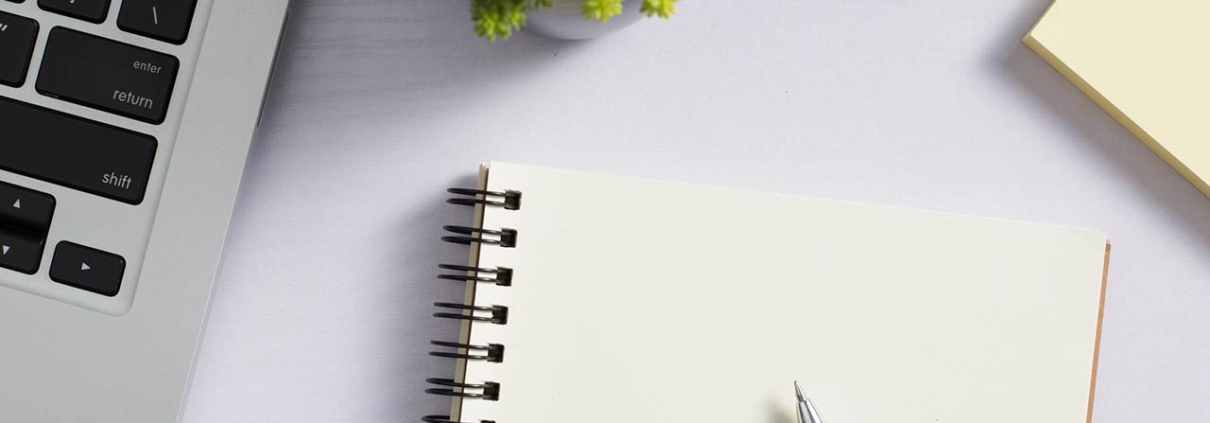 top view of a white desk with laptop and supplies