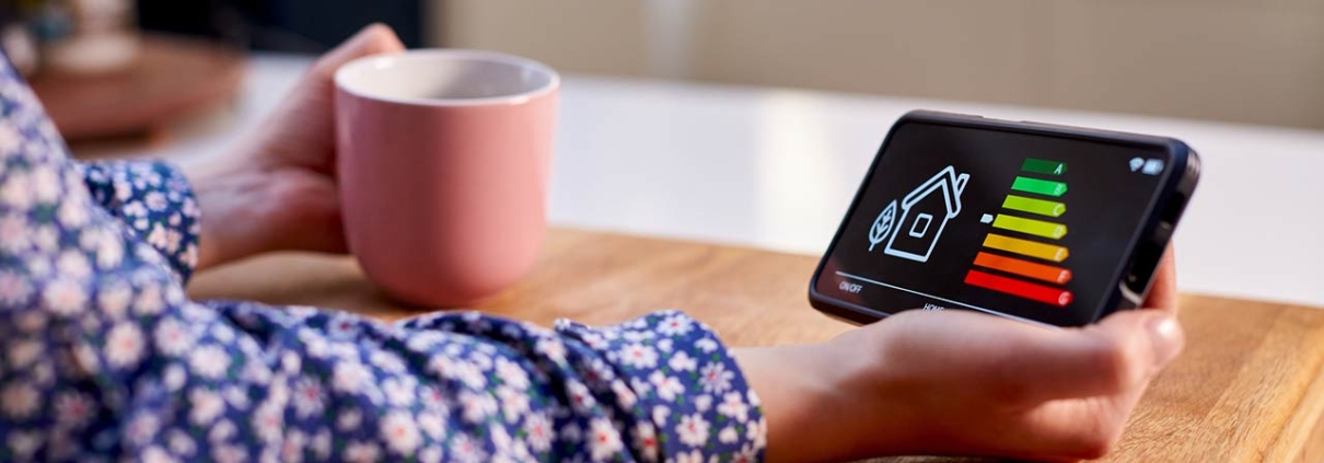 Close Up Of Woman Holding Smart Energy Meter In Kitchen Measuring Energy Efficiency