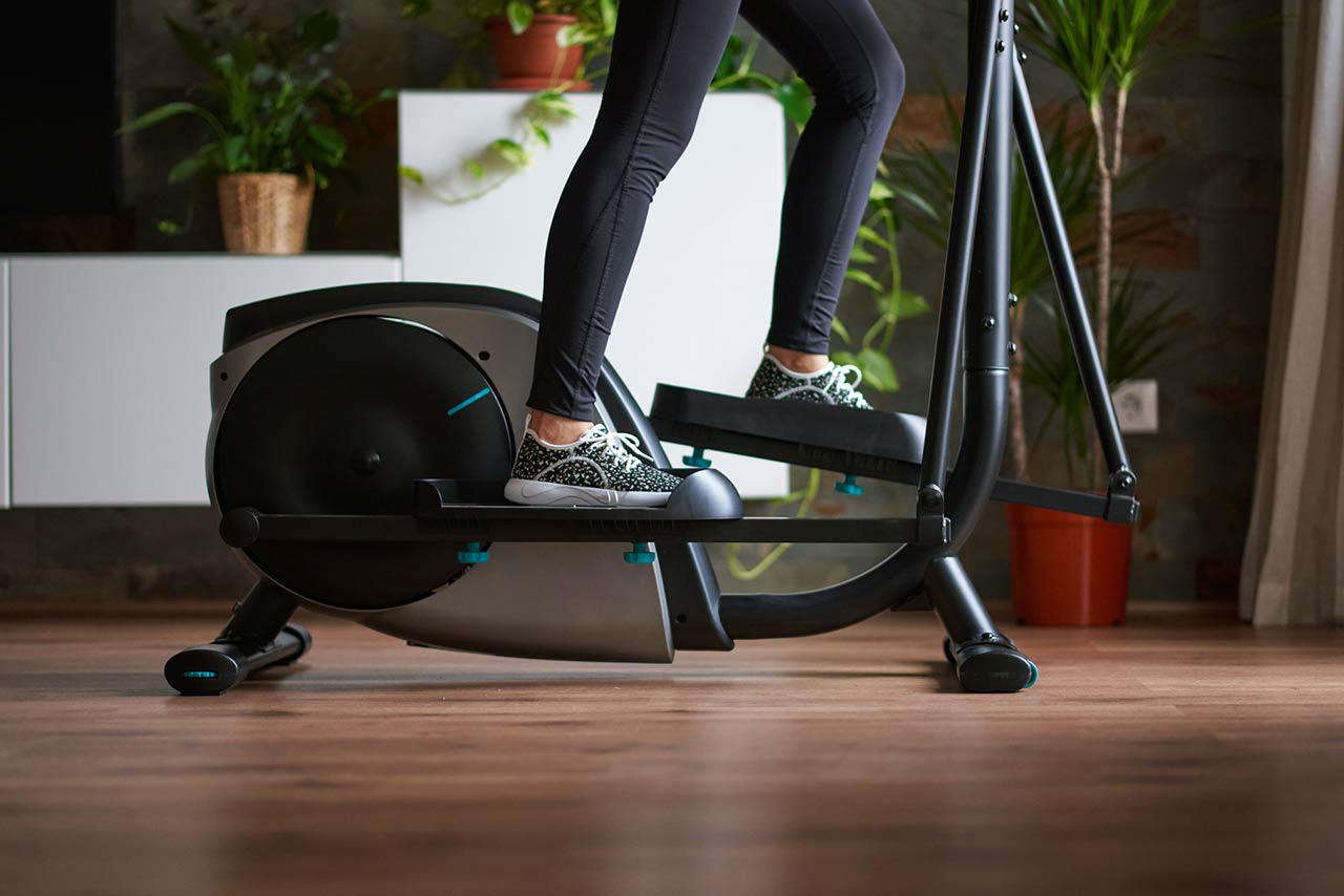 A womans legs training on smart elliptical trainer indoors at home in daylight with natural light