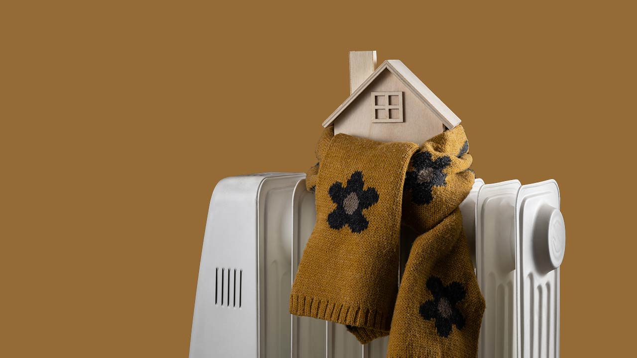 Wrapped in a warm scarf, a symbolic wooden house stands on an electric radiator