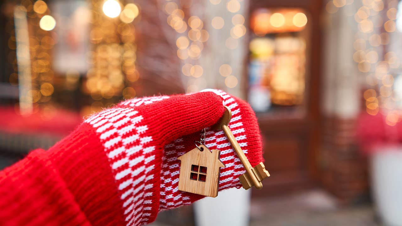 Hand in red mitten holding key with house shaped keychain